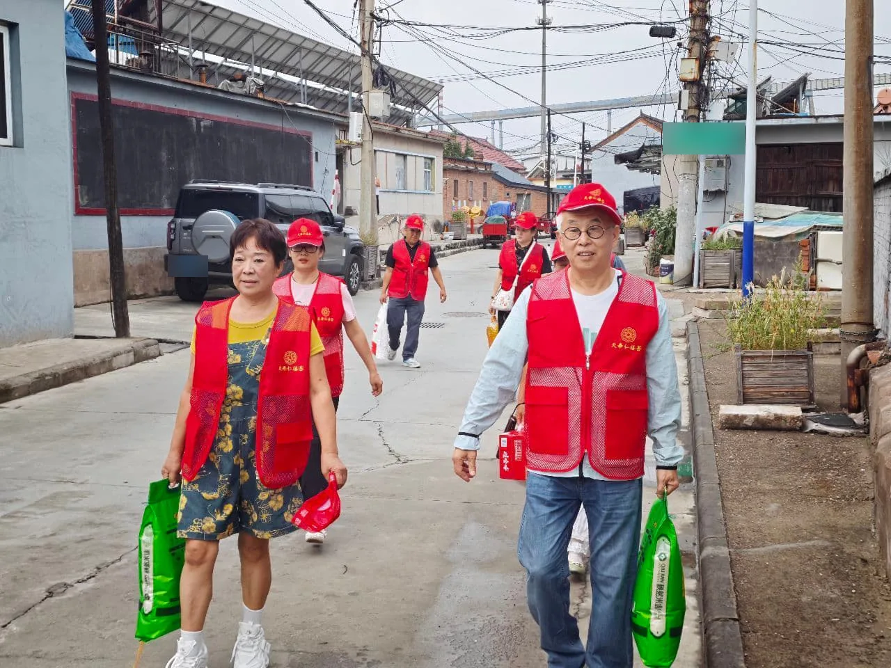 孙玉琴公益实践:志愿者手提米、面等生活用品,前往慰问家庭。