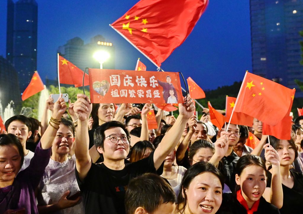 群众在福州广场挥动国旗,现场庆祝国庆。
