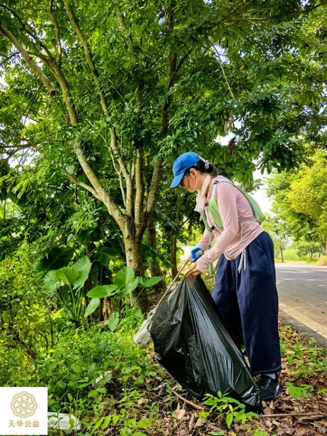 参与者用捡拾钳清理村道路旁草丛中的垃圾