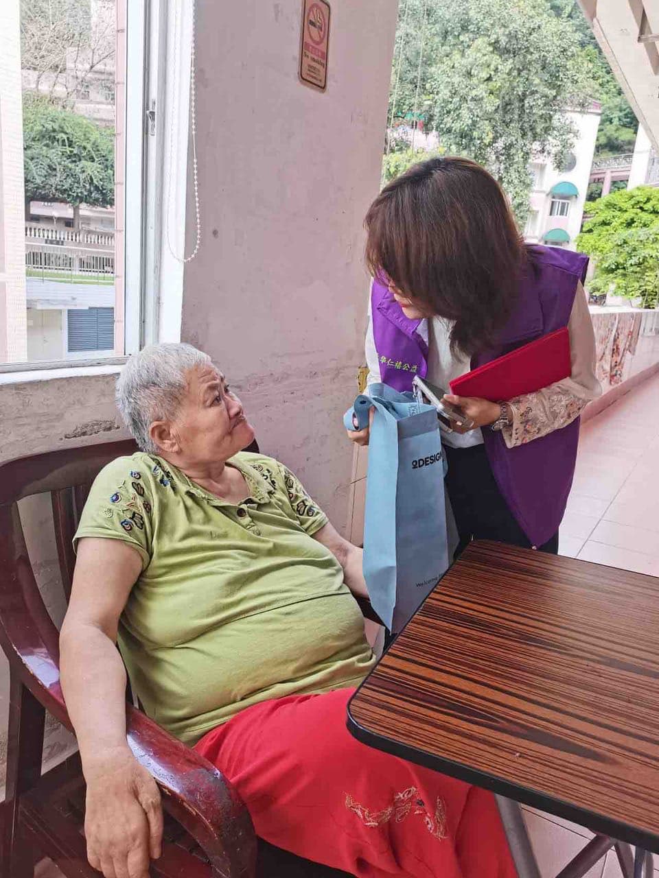 团队成员俯身倾听老人的近况